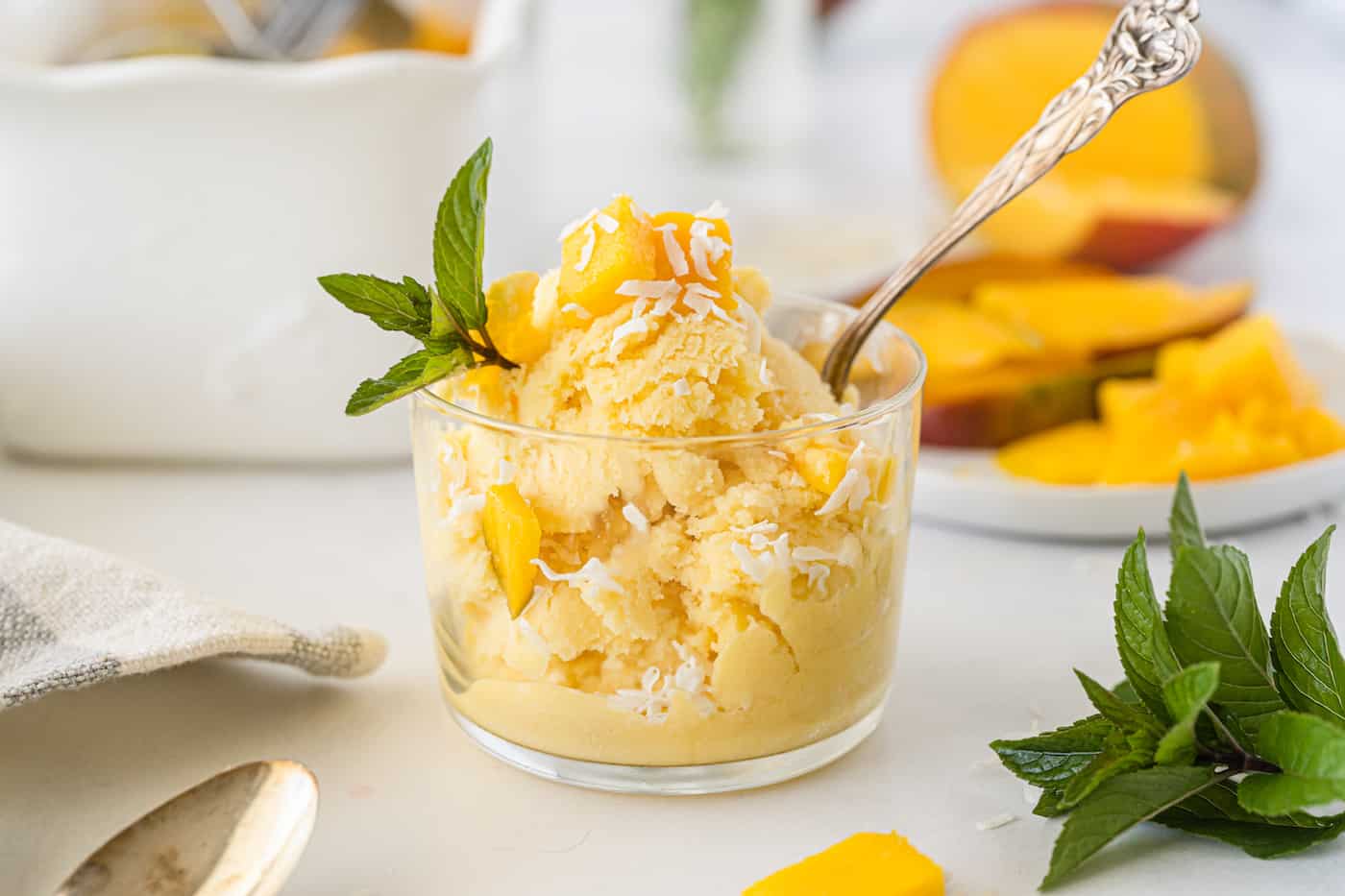 Close-up of a scoop of mango ice cream, its bright yellow hue and smooth texture visible, set against a backdrop of fresh mango slices, capturing the essence of tropical indulgence.