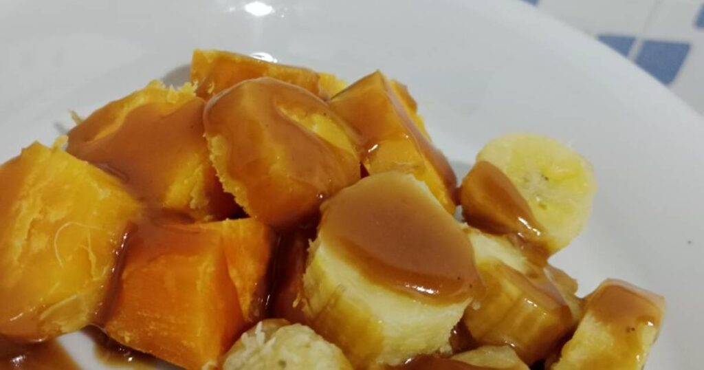 Pisang rebus gula yang manis dan harum, disajikan hangat dengan taburan kelapa parut untuk tambahan rasa gurih