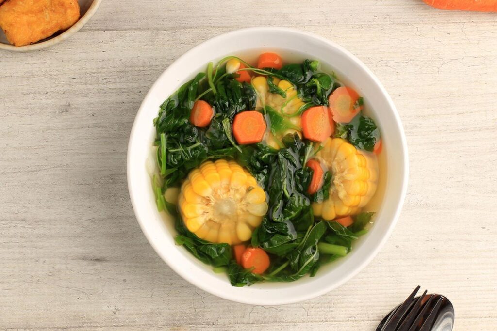 Semangkuk sayur asem segar dengan isian lengkap seperti jagung, labu siam, kacang panjang, dan melinjo