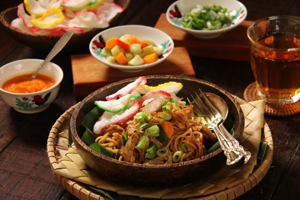 Sepiring mie goreng Jawa dengan tekstur lembut, bumbu rempah yang kaya, dan tambahan suwiran ayam serta irisan sayuran segar