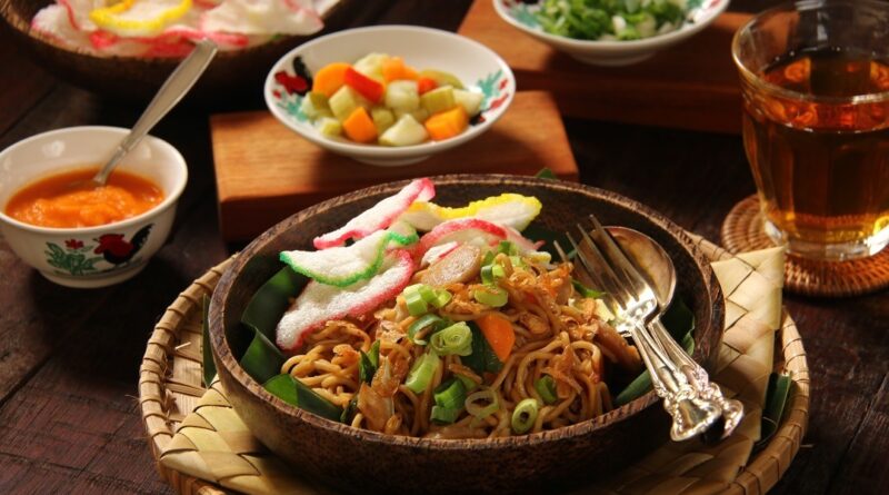 Sepiring mie goreng Jawa dengan tekstur lembut, bumbu rempah yang kaya, dan tambahan suwiran ayam serta irisan sayuran segar