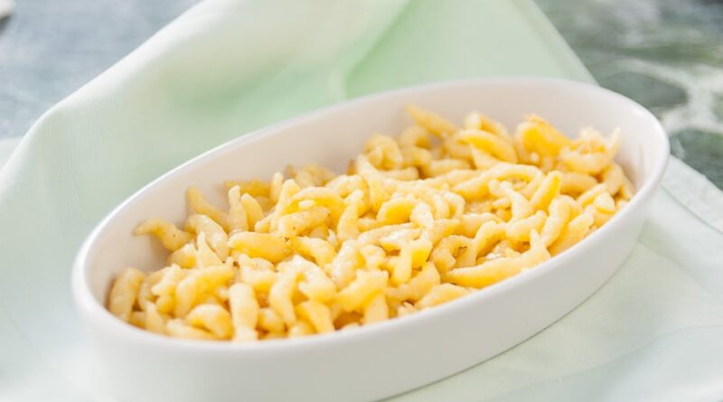 Crispy golden-brown Spätzle served on a plate with fresh lemon wedges and potato salad