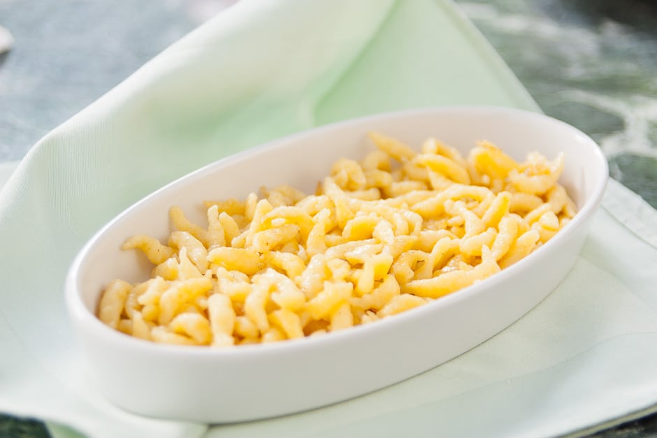Crispy golden-brown Spätzle served on a plate with fresh lemon wedges and potato salad